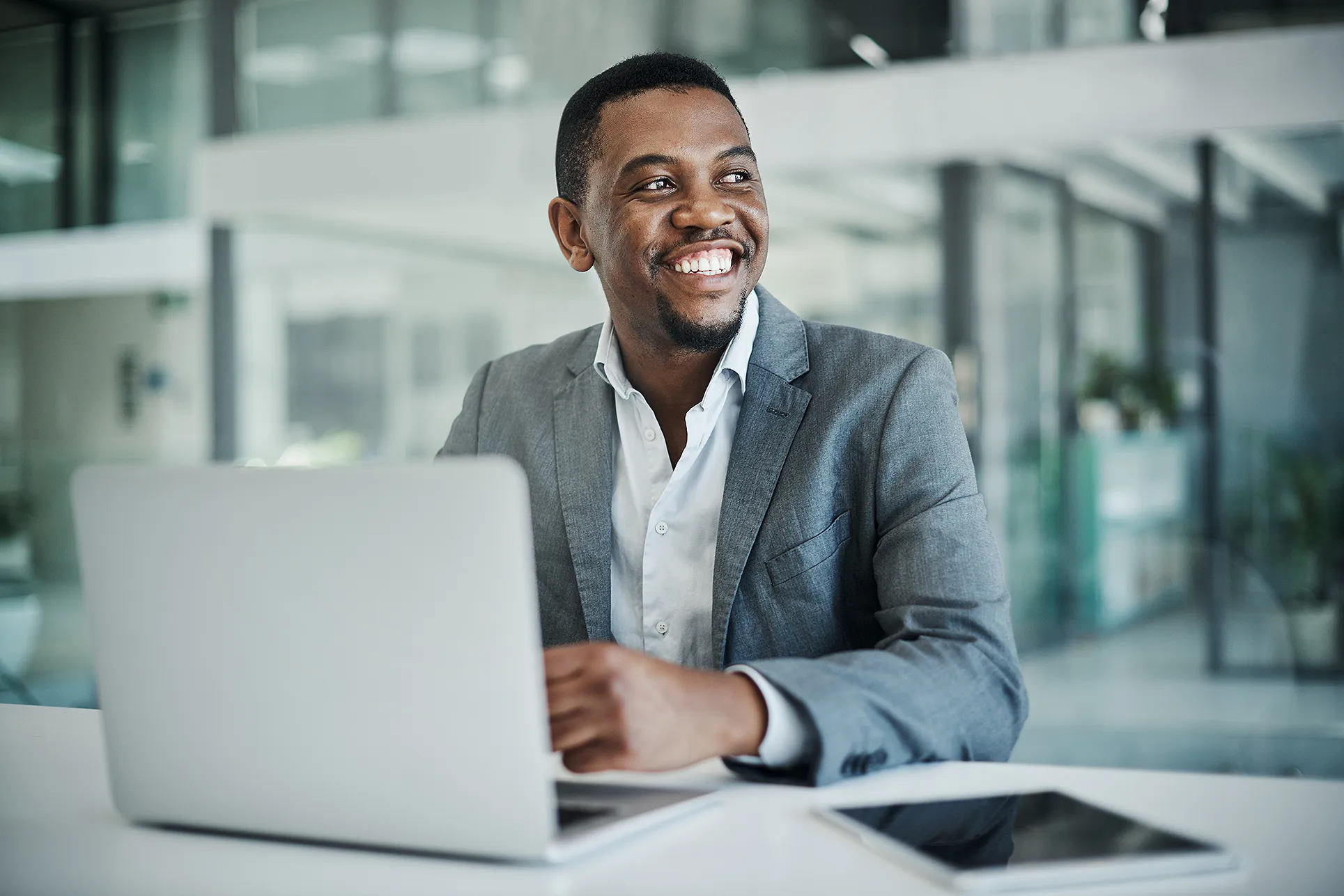 Young man smiling sitting at his desk with laptop