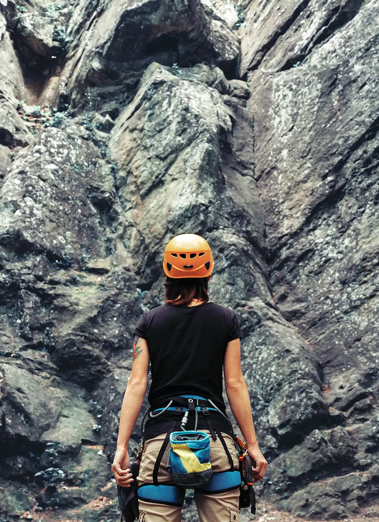 Climber woman standing in front of a stone rock outdoor